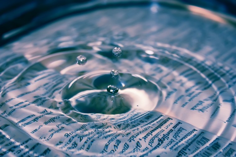 A droplet of water starts a ripple on top of a book.
Image sourced via Pixabay.