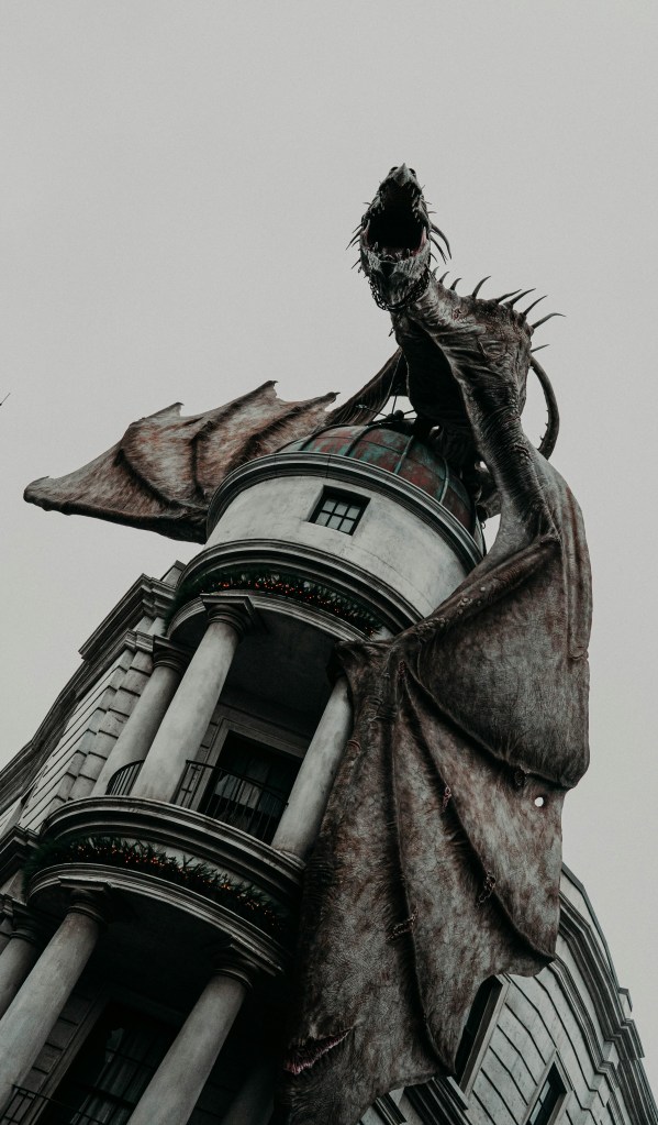 Black and white photo of a dragon perched atop a second story balcony, mouth open in a scream.
© Sean Thomas on Unsplash. 